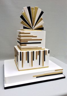 a three tiered cake with black and gold stripes on it's sides, topped by an art deco fan