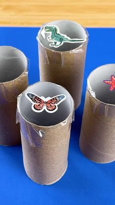 three cups with stickers on them sitting on a blue surface