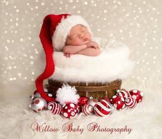 a newborn baby is sleeping in a basket with christmas ornaments around him and wearing a santa hat