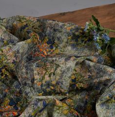 a close up of a cloth with flowers on the table next to it and a vase