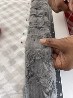 a man is measuring the length of a fur rug on a table with scissors and tape