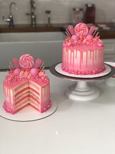 two cakes with pink frosting and candy decorations