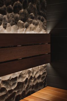 a wooden bench sitting in front of a wall with rocks on it's sides