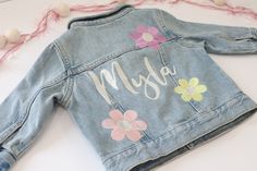 Custom Embroidered Denim Name Jacket With 3 Flowers!  Choose color flowers or shades of pink flowers  Old Navy Jackets *Runs small in my opinion  Toddler: 100% Cotton  Light Denim Jackets 3-6 months 6-12 months 12-18 months 2T 3T 4T 5T Girls: 95% Cotton, 5% Spandex  Medium Denim Jackets S (6/7) M (8) L (10/12) XL (14/16) Cream thread for name, unless specified.  Leave any flower or name thread color choices in notes otherwise I'll do it just like pictured!  Lots more thread color options, so if Spring Denim Jacket With Floral Print, Spring Cute Denim Jacket With Pockets, Spring Cotton Outerwear With Floral Applique, Pink Cotton Denim Jacket For Spring, Cute Long Sleeve Denim Jacket For Spring, Pink Denim Outerwear For Summer, Light Wash Denim Jacket For Spring, Spring Light Wash Denim Jacket, Pink Cotton Outerwear With Floral Embroidery