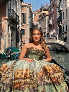 a woman sitting on top of a boat in a river next to buildings and boats