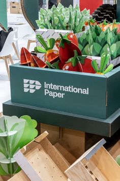 the international paper sign is on display in front of other boxes with plants inside it