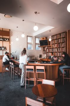 people sitting at tables in a restaurant with bookshelves and shelves on the wall