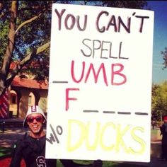 a man holding a sign that says you can't spell umb f for ducks