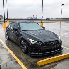 a black car is parked in the wet parking lot