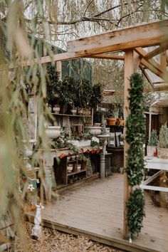 an outdoor garden with potted plants on the deck and wooden pergolated area