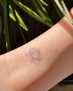 a woman's arm with a small flower tattoo on the left side of her arm