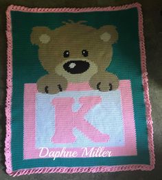 a crocheted baby blanket with a teddy bear on it and the letter k