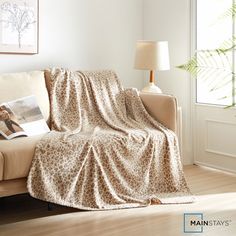 a living room with a couch covered in a leopard print blanket next to a lamp