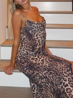 a woman sitting on some stairs wearing a leopard print dress