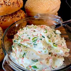 a glass bowl filled with coleslaw next to bagels