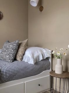 a bedroom with a bed, night stand and vases on the side table in front of it