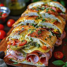 ham, cheese and tomato sandwich cut in half on a cutting board with tomatoes around it