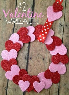 valentine wreath made out of paper hearts on a wooden surface with text overlay that says,