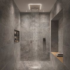 a shower head in the middle of a walk - in shower with grey tile walls and floor