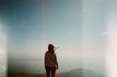 a woman standing on top of a hill with her hair blowing in the wind,