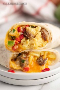 two breakfast burritos sitting on top of a white plate