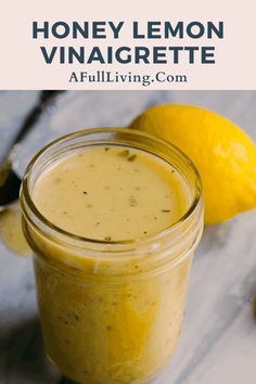 a mason jar filled with honey lemon vinaigrette next to two lemons