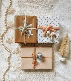 three wrapped presents sitting on top of a bed next to a christmas tree and other decorations