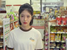 a woman standing in front of a grocery store aisle with food items on the shelves