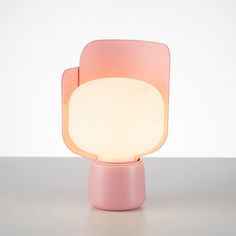 a pink lamp sitting on top of a table next to a white wall and floor