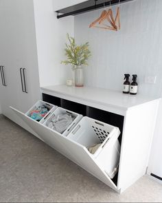 a white cabinet with two open drawers and clothes in the bottom drawer next to it