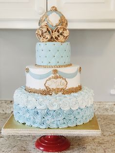 a three tiered cake with blue and white frosting, gold crown on top