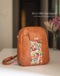 a brown purse sitting on top of a table next to a vase with flowers in it