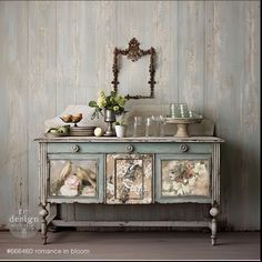 an old dresser with pictures on it and flowers in vases next to the drawers