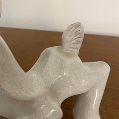 a white ceramic figurine sitting on top of a wooden table