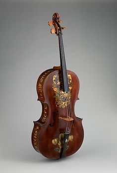 an old violin is sitting upright on a gray background, with the strings still attached to it