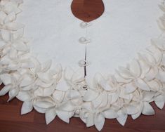 a wreath made out of white fabric with buttons and flowers on the front, sitting on a wooden floor