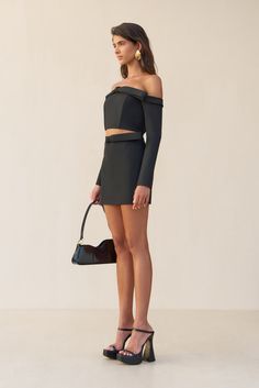 A tailored mini skirt with a bow detail at the waist and a hidden center back zip. — Mini length — A-line silhouette — Bow detail at waist — Center back zip — Wear with the Valia Top Chic Mini Skort For Night Out, Chic Mini Skirt For Party, Elegant Mini Skirt For Going Out, Chic Mini Skort For Party, Elegant Black Mini Skort, Modern Mini Skirt For Party, Chic Mini Skort For Going Out, Fitted Mini Skort For Cocktail, Sleek Skort For Night Out In Mini Length