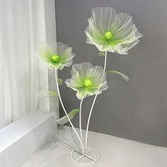 three green flowers are in a white vase