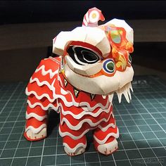 a red and white dragon figurine sitting on top of a table next to a knife