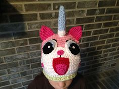 a child wearing a crocheted hat with a unicorn face on it's head