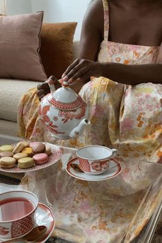 a woman sitting at a table with some tea and cookies on the tray next to her