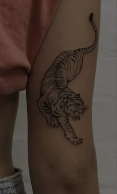 a person with a tiger tattoo on their arm and leg, standing in front of a white wall