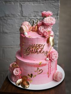 a pink birthday cake decorated with flowers and decorations