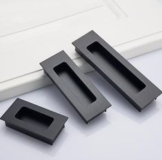 three black plastic objects sitting on top of a white table next to a door handle