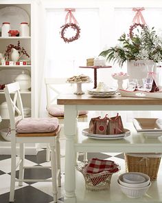 a dining room table and chairs in front of a window with wreaths on the windowsill