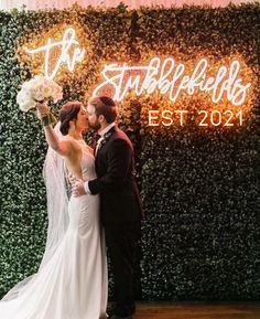 a bride and groom standing in front of a wall with the word'tufflefells'written on it