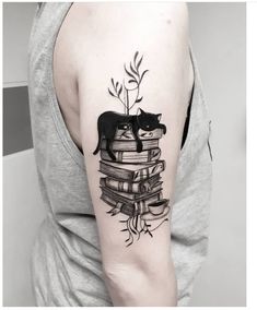 a black cat sitting on top of a stack of books with leaves and branches around it