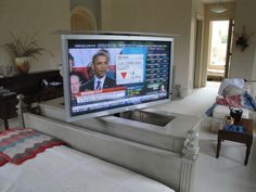 a flat screen tv sitting on top of a white bed