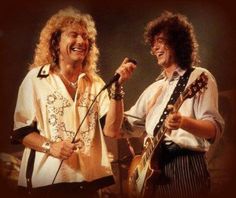 two men standing next to each other on stage with guitars and microphones in their hands