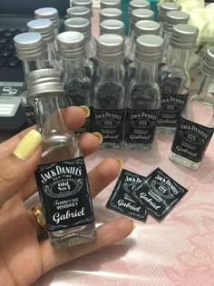 a hand holding a miniature bottle of jack daniels gin with small bottles in the background